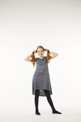 A girl in a gray dress stands on a white clean background.