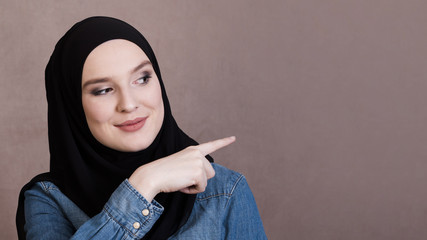 Smiling pretty woman pointing at background