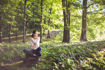 Beautiful woman meditating in the forest on a sunny morning