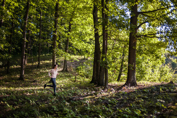 Young girl jogging in the woods on a sunny morning.