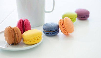 Colorful macarons and coffee cup on white background, close up view