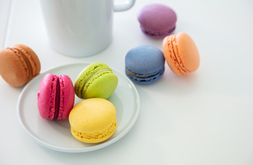 Colorful macarons and coffee cup on white background, close up view
