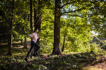 Young girl jogging in the woods on a sunny morning.
