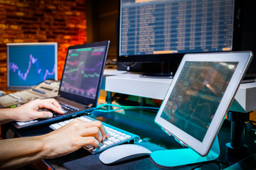Businessman trading stocks with desktop, laptop and tablet computer