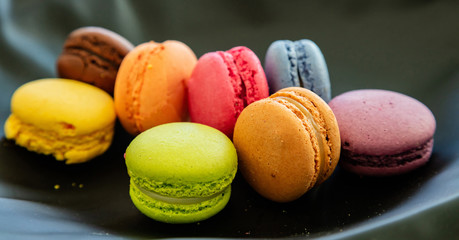 Colorful macarons on black background, close up view