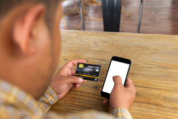 Men holding a credit card and are doing business on the internet in a mobile phone on a background table.