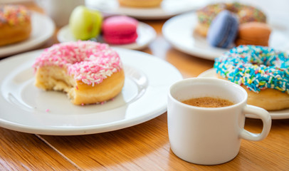 Donuts macarons and coffee on wood, close up view with details