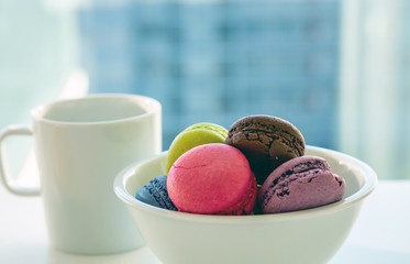 Colorful macarons and coffee cup on white background, close up view