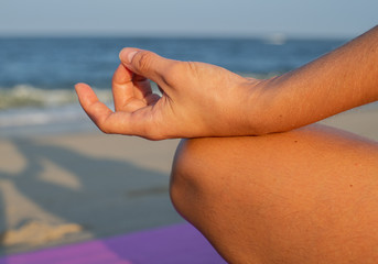 Close-up female hand in gyan mudra and lotus position. Woman practicing yoga and meditating.