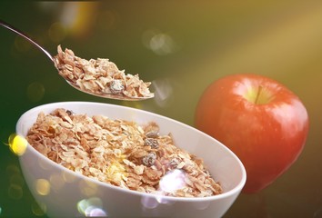 Raw oats in bowl and fruit salad, apples on the wooden table