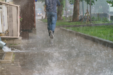 Raining day in the city at summer time. A wet young man running in the rain. Texture of strong,...