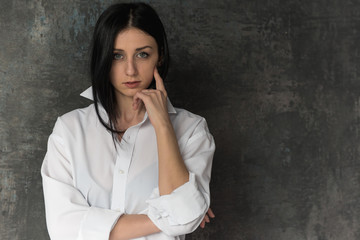 portrait of a young, pretty girl who is dressed in a white men's shirt and is in a light room, on a gray background