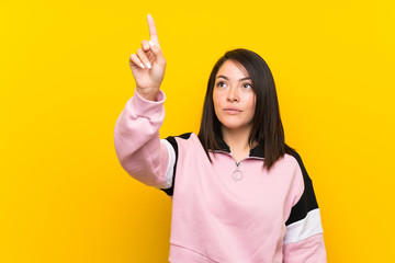 Young Mexican woman over isolated yellow background touching on transparent screen