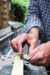 Close up of mans hands working with a plane on wooden plank