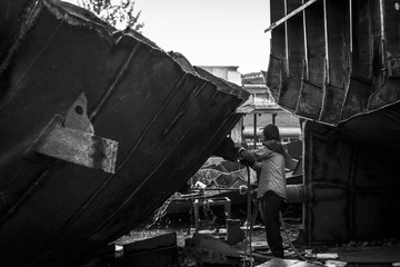 Zhuhai/China – April, 23rd 2017: Shipbreaking Yard in Zhuhai, worker dismantling with scrap metal, using gas to cut barge, ship