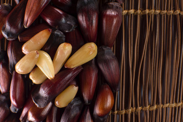 Brazilian Pinion fruit in wood background in the side of the frame with some peeled seen from above