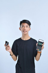 Young asian man showing a credit card / a debit card and an Electronic Data Capture (EDC) machine for easy and fast financial transaction