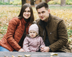 Young family sitting on bench in autumn park