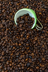Green cup among a lot of coffee beans.