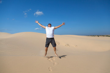 concept of freedom, a man in the desert jumps up on a hill barefoot on the sand