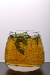Refreshing drink with gas bubbles. Nalit in a transparent glass. It laid crushed ice. Decorated with mint leaves.