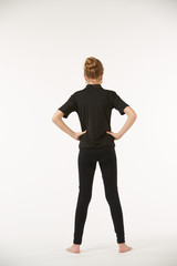 A school-age girl in black clothes stands on a white clean background.