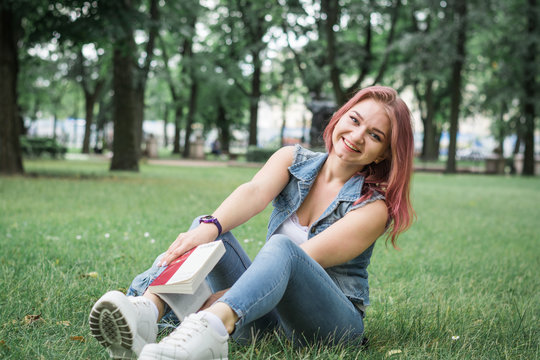 fun photo, hipster girl with red hair laughs in the park on the green grass
