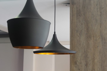 black colored light fixture, at the reception of a building containing a golden light inside.