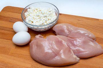 raw chicken breast, cereals, eggs, farm cottage cheese close up on wooden background protein healthy diet concept eco product sports nutrition