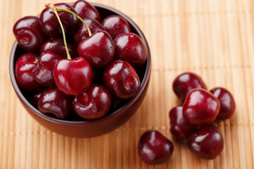 Ripe and juicy cherry berries on a wooden background in a brown cup