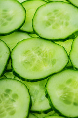 Slices of green fresh cucumber backlit as a textural background