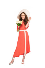 full length view of elegant woman in hat and dress holding white tulips isolated on white