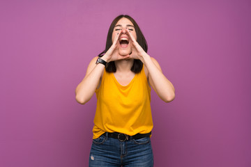 Young woman over isolated purple wall shouting and announcing something