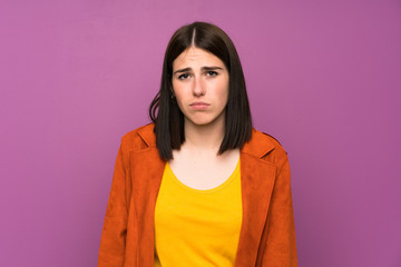 Fototapeta premium Young woman with a coat over isolated purple background sad