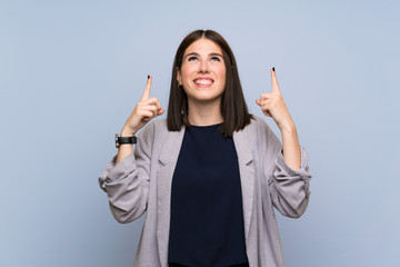 Young woman over isolated blue wall pointing up a great idea