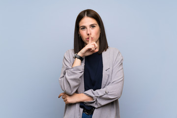 Young woman over isolated blue wall showing a sign of silence gesture putting finger in mouth
