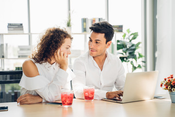 Multi-ethnic young business couple using notebook laptop together in office. Information technology, education,startup business.Happy business couple having fun at work in summer.With copy space.
