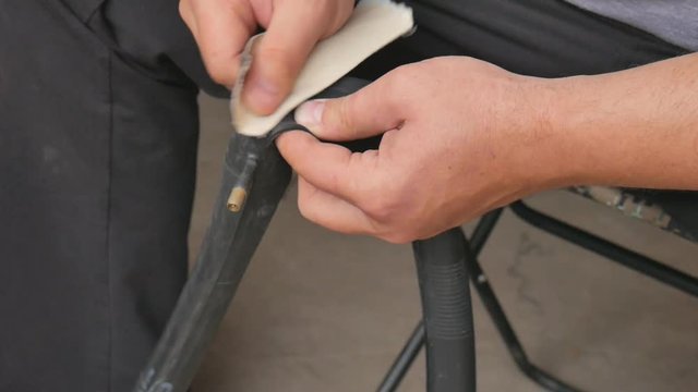Cyclist or mechanic cleans a punctured tire bicycle. Close up of hands and bicycle flat tire tyre. A man repairs a bicycle wheel pierced.