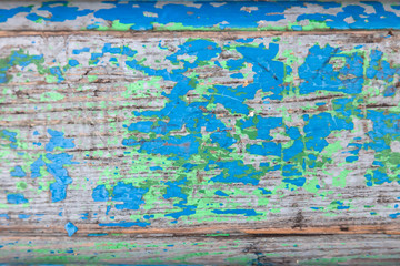 Fototapeta na wymiar Close-up on a wooden flat surface with old peeling paint of different colors with cracks on three boards. Blue, green and red color on the tree.