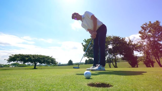 Male player is striking and the ball is falling into the hole