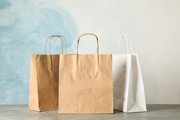 Paper bags on grey table against blue background, copy space