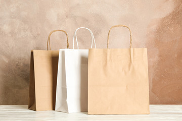 Paper bags on white table against brown background, copy space