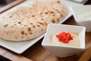 Brick Oven Bread and hummus dipping sauce on a wooden dish