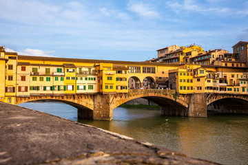 Fototapeta premium Golden hour at the Ponte Vecchio a medieval stone closed-spandrel segmental arch bridge over the Arno River in Florence