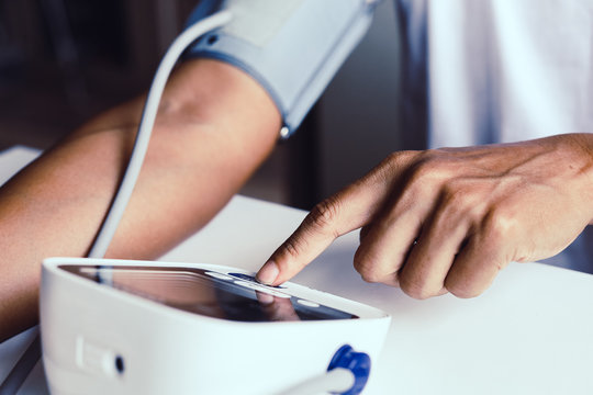 Close-up man measure pressure by yourself in room.
