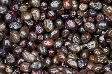 Smoked black market fresh black olives as background