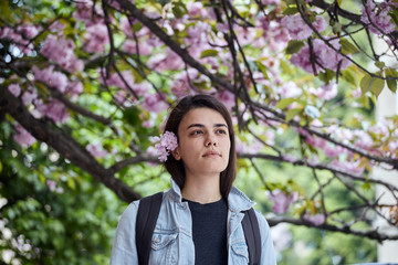 Young woman posing on the background of blooming sakura