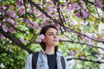 Young woman posing on the background of blooming sakura