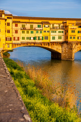Fototapeta na wymiar Golden hour at the Ponte Vecchio a medieval stone closed-spandrel segmental arch bridge over the Arno River in Florence