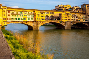 Fototapeta premium Golden hour at the Ponte Vecchio a medieval stone closed-spandrel segmental arch bridge over the Arno River in Florence